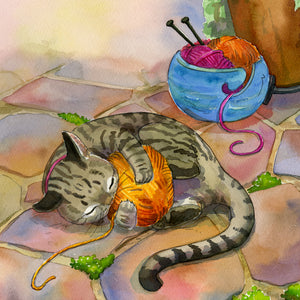 Tabby cat playing with ball of orange yarn on a stone patio.
